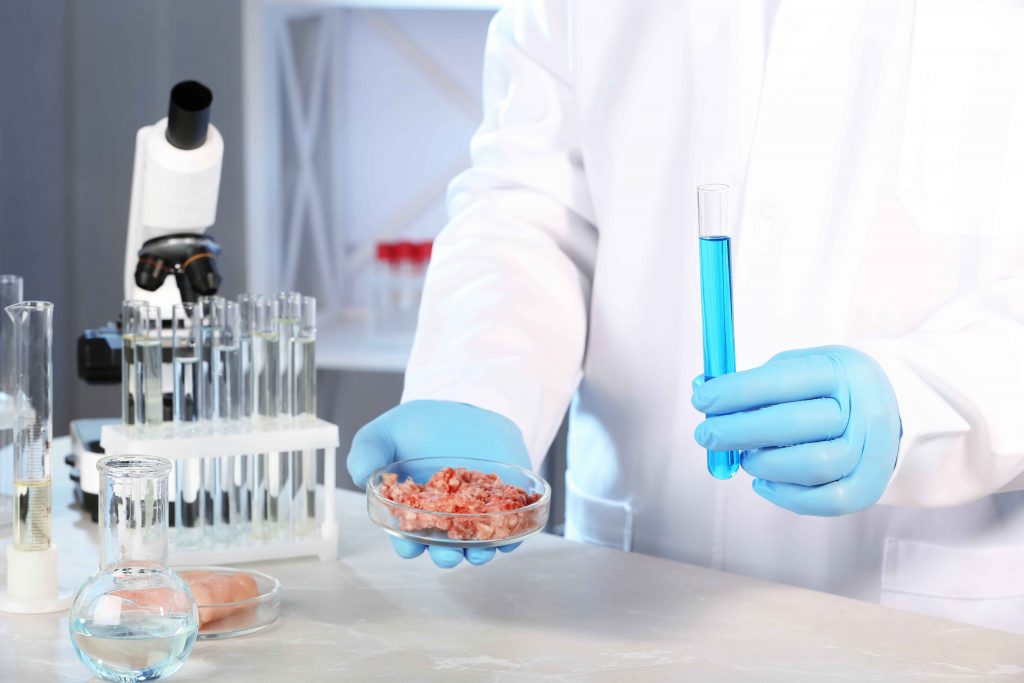 A scientist holding a protein sample and a test tube in a laboratory