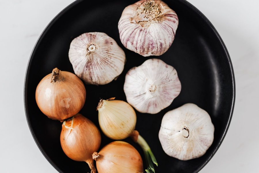 Whole onions and garlic bulbs on a black plate